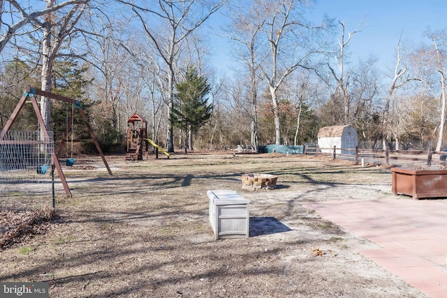 view of yard featuring a storage shed, fence, playground community, and an outdoor structure