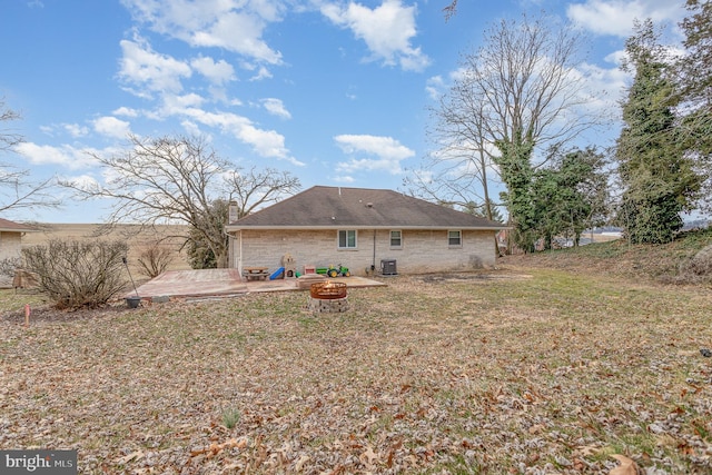 rear view of house featuring cooling unit, a fire pit, a yard, a chimney, and a patio area