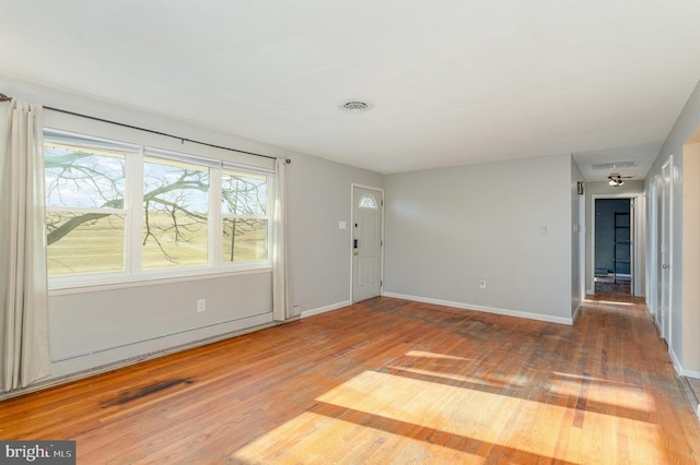 unfurnished room with wood finished floors, visible vents, and baseboards