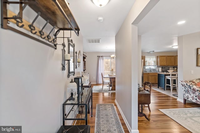 foyer entrance featuring baseboards, visible vents, and wood finished floors