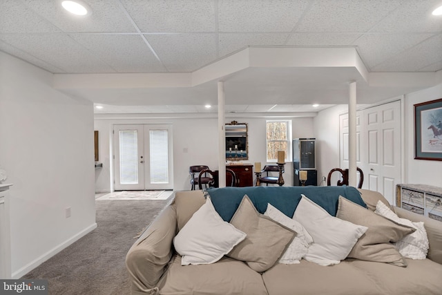 living area featuring baseboards, a drop ceiling, carpet flooring, and french doors