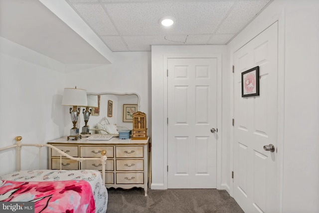 bedroom with a paneled ceiling and dark colored carpet