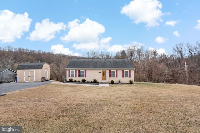 view of front of house with an outbuilding, a storage unit, a front lawn, and aphalt driveway