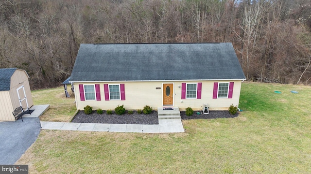 view of front of house featuring a storage shed, an outdoor structure, and a front yard