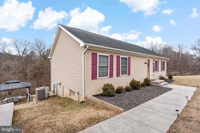 view of front of house with a shingled roof, a front yard, a gazebo, and central air condition unit