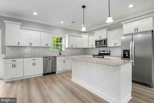 kitchen with stainless steel appliances, hanging light fixtures, white cabinetry, and a center island