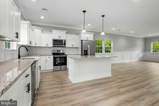 kitchen featuring white cabinetry, a kitchen island, appliances with stainless steel finishes, and a sink