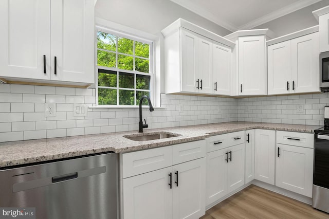 kitchen with white cabinets, light stone counters, stainless steel appliances, and a sink