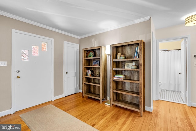 foyer with light wood-style floors, baseboards, and crown molding