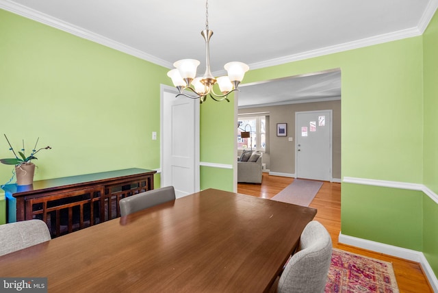 dining area featuring ornamental molding, a notable chandelier, and wood finished floors