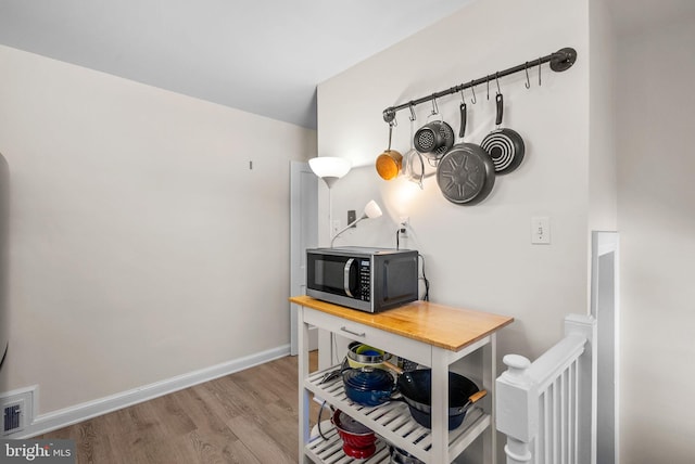 office space with wood finished floors, visible vents, and baseboards