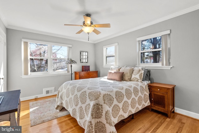 bedroom featuring crown molding, light wood-type flooring, visible vents, and baseboards