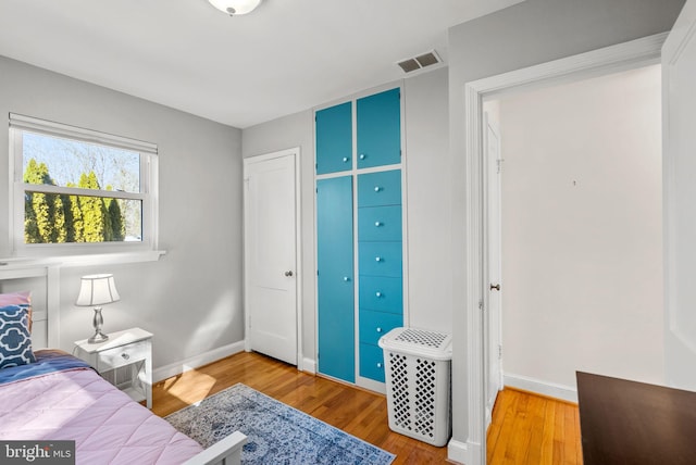 bedroom with wood finished floors, visible vents, and baseboards