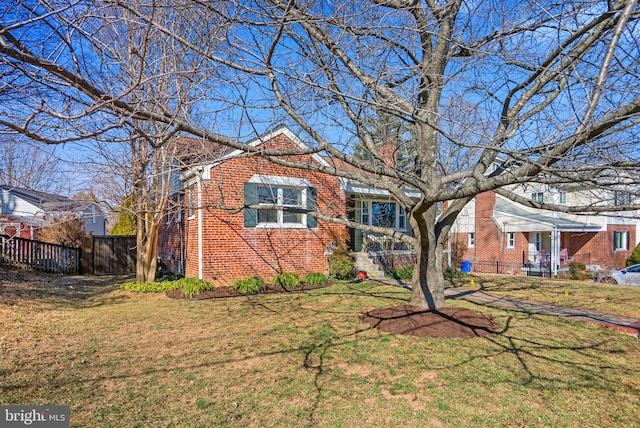 view of front of property featuring brick siding, a front lawn, and fence