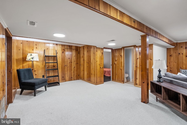 living area featuring carpet floors, ornamental molding, wood walls, and visible vents