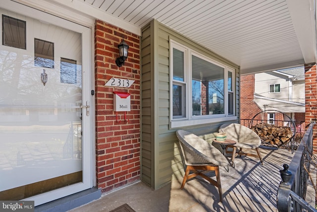 doorway to property with covered porch and brick siding