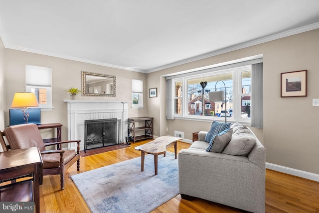 living area featuring ornamental molding, a fireplace, wood finished floors, and baseboards