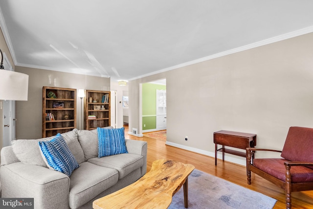 living area with light wood-type flooring, visible vents, baseboards, and crown molding