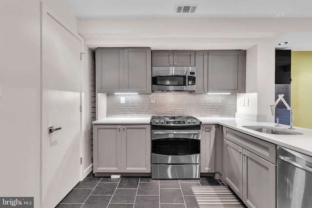 kitchen featuring appliances with stainless steel finishes, gray cabinets, and a sink