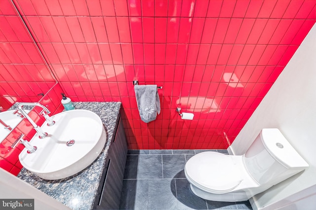 bathroom featuring tile patterned flooring, tile walls, vanity, and toilet