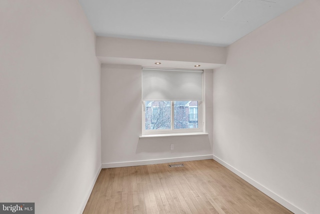 empty room with visible vents, baseboards, and hardwood / wood-style flooring