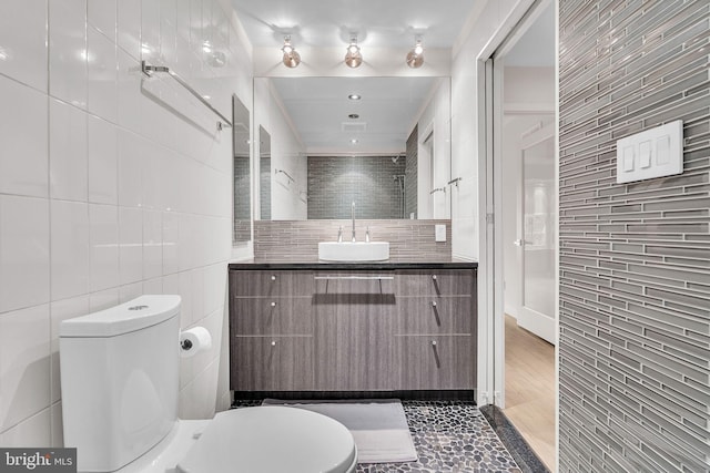 bathroom featuring toilet, tile walls, and vanity