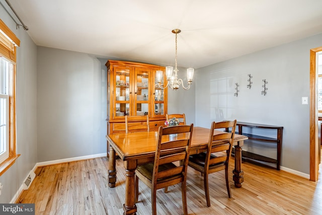 dining room with baseboards, light wood-style floors, visible vents, and a chandelier