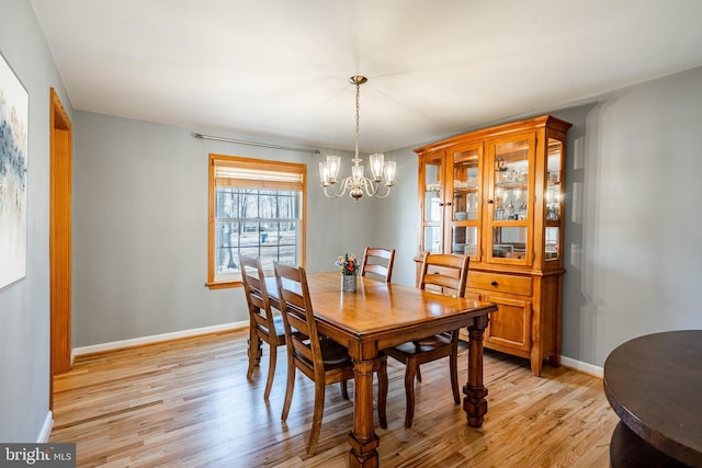 dining room with an inviting chandelier, baseboards, and light wood-type flooring