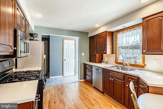 kitchen featuring light wood finished floors, light countertops, recessed lighting, appliances with stainless steel finishes, and a sink