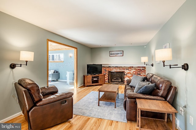 living area with a fireplace, wood finished floors, and baseboards