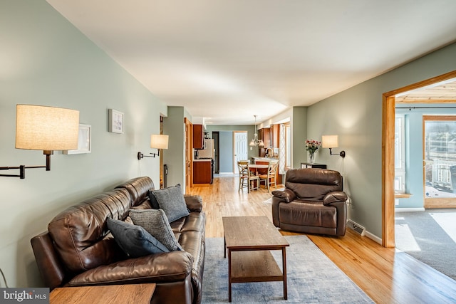 living room with visible vents, baseboards, and light wood-style floors