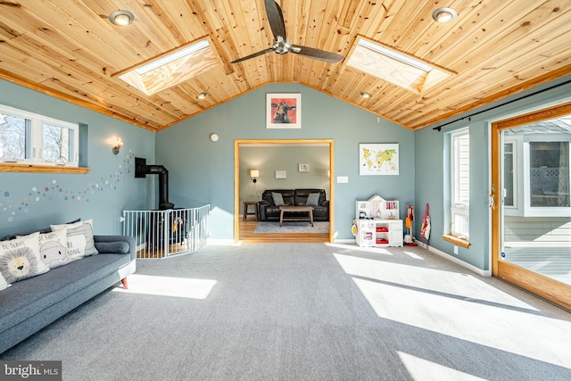 carpeted living area featuring vaulted ceiling with skylight, wood ceiling, and baseboards