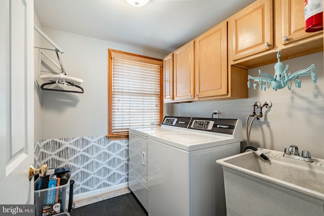 clothes washing area featuring washer and clothes dryer, cabinet space, and a sink