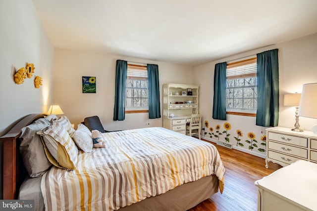 bedroom with multiple windows and wood finished floors