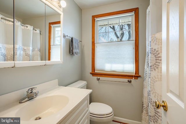 full bathroom with vanity, toilet, baseboards, and a wealth of natural light