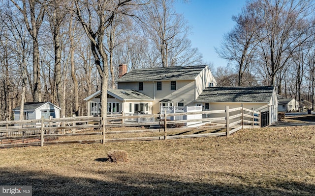 view of front facade featuring fence private yard, a chimney, and a front yard