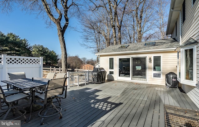 deck with area for grilling, outdoor dining space, and fence