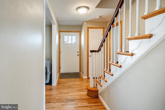 entryway with stairway, light wood-style floors, and baseboards