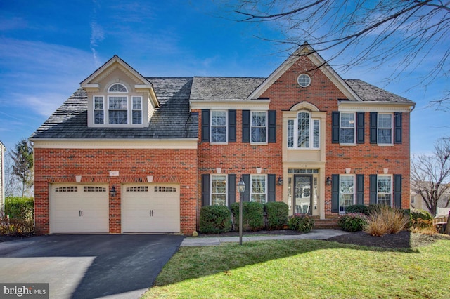 view of front facade featuring a garage, brick siding, a front yard, and aphalt driveway