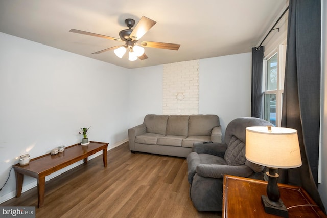 living room with ceiling fan, baseboards, and wood finished floors