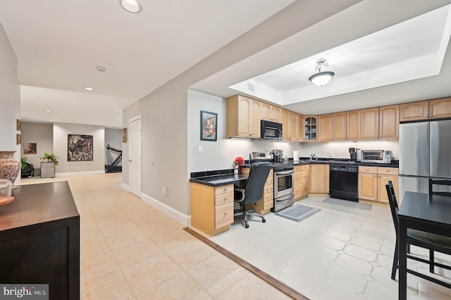 kitchen with baseboards, light brown cabinetry, black appliances, dark countertops, and a raised ceiling