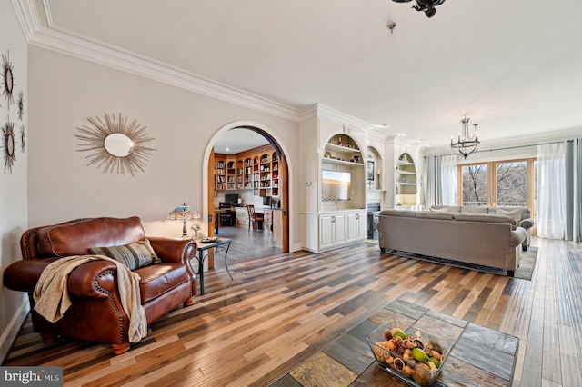 living area featuring an inviting chandelier, light wood-style flooring, crown molding, and arched walkways