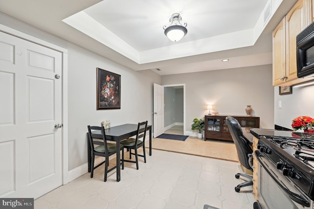 home office with visible vents, light floors, baseboards, and a tray ceiling