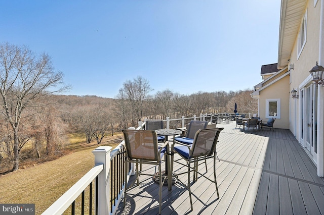 deck with a view of trees and outdoor dining space