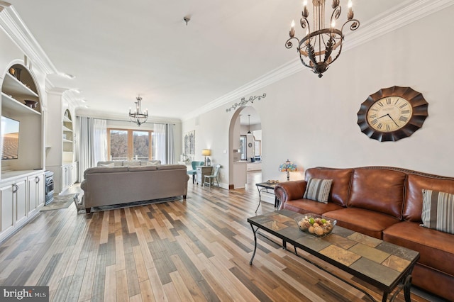 living area featuring baseboards, light wood finished floors, an inviting chandelier, arched walkways, and crown molding