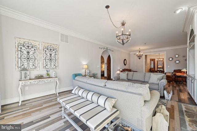 living area with wood finished floors, visible vents, arched walkways, crown molding, and a chandelier