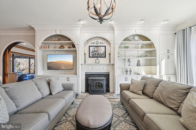 living room featuring built in features, a chandelier, and ornamental molding