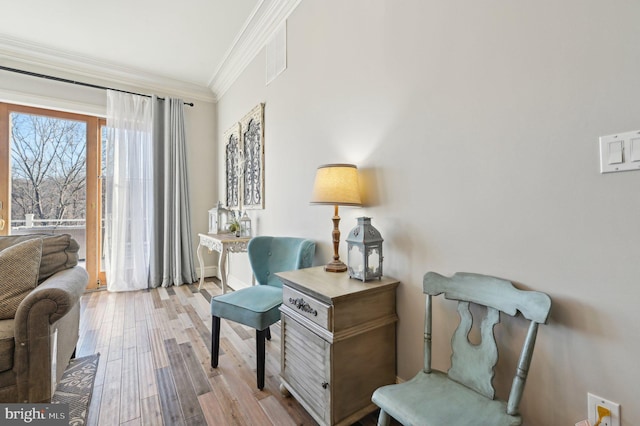 sitting room featuring visible vents, wood finished floors, and ornamental molding