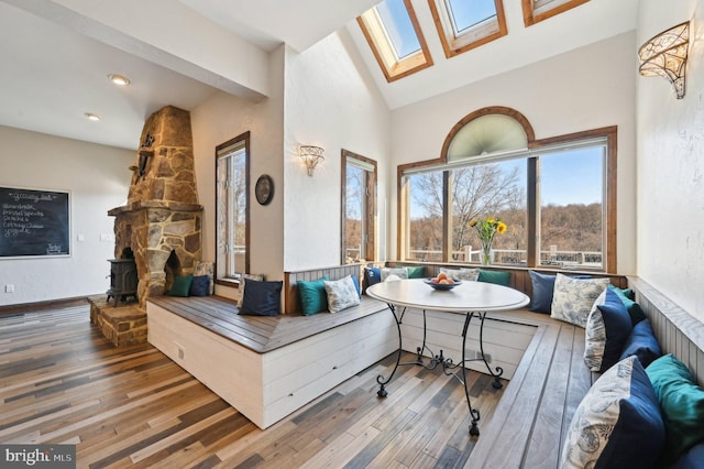 living area featuring high vaulted ceiling, a skylight, recessed lighting, wood-type flooring, and breakfast area