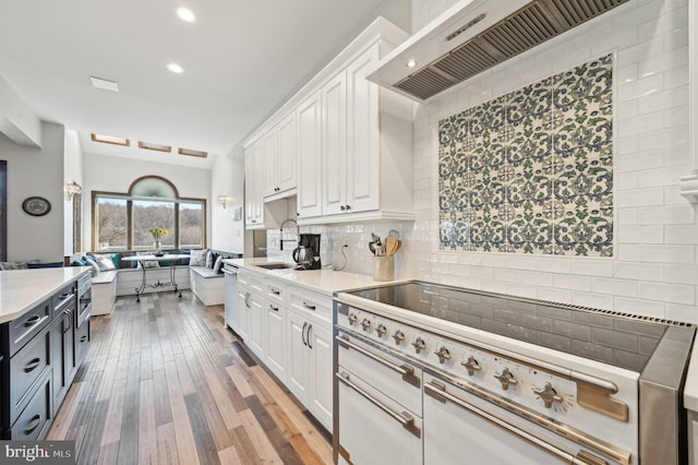 kitchen with white cabinetry, stove, custom range hood, and open floor plan